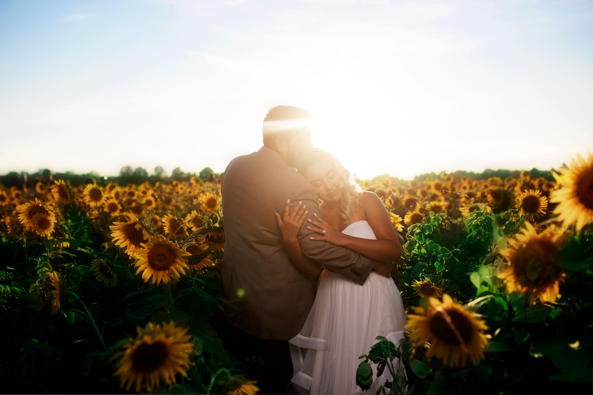 Couple embracing in a sunflower field at golden hour