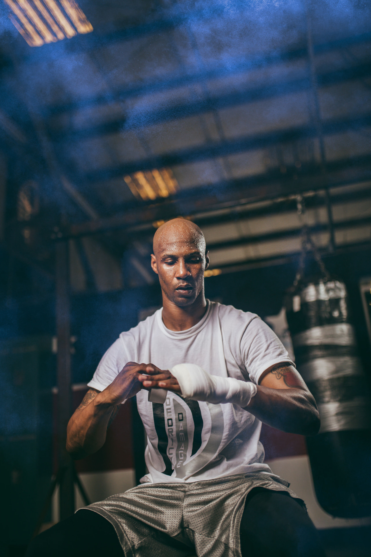 Boxer wrapping his hands in a gym lit with blue haze